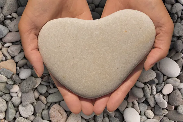 Hands holding a heart-shaped stone