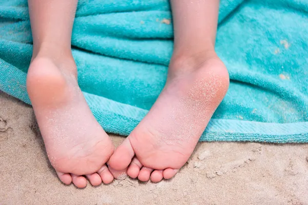 Little girl feet on a beach towel