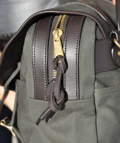 Closeup of a half-opened zipper on a green bag.