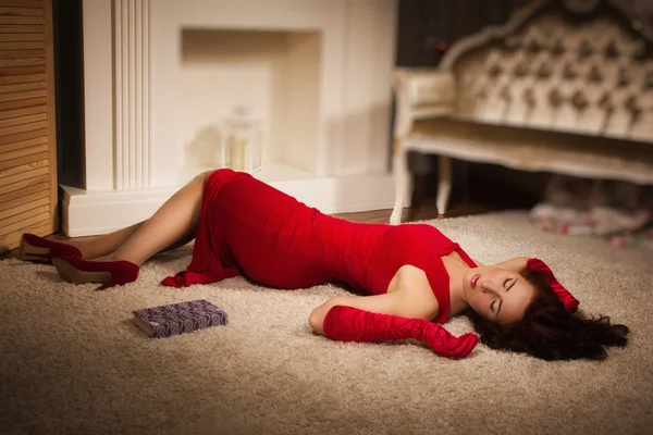 Fashionable lady in a red dress lying on the floor