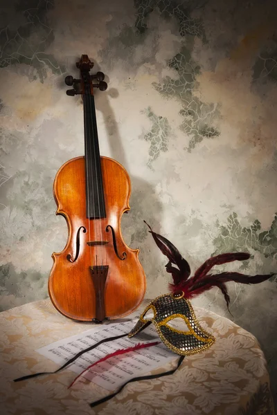 Violin with score and mask on a stone wall