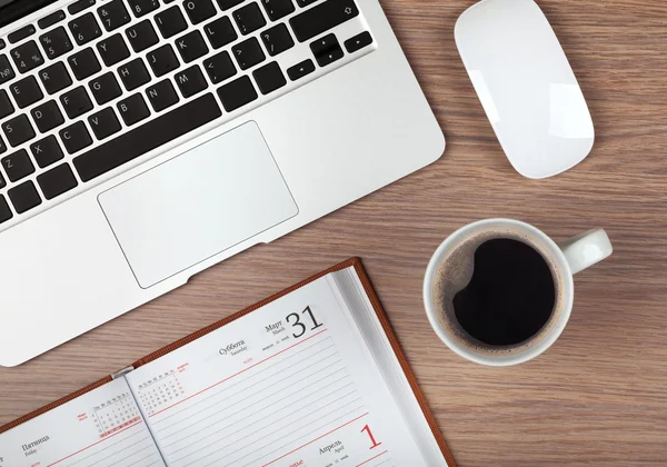 Notepad, laptop and coffee cup on wood table