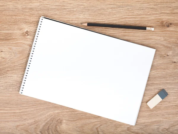 Blank notepad, pencil and eraser on the wooden table