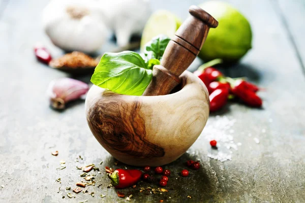 Wooden Mortar and Pestle and chilli peppers, herbs and spices