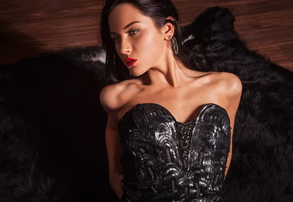 Beauty fashion Women Portrait. Model pose in luxury dress on black fur.