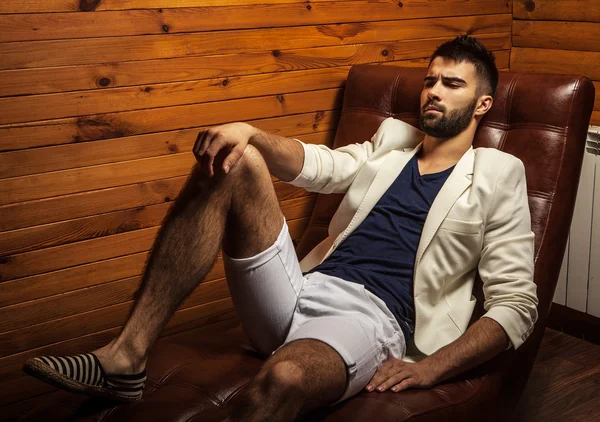 Handsome young man in white suit relaxing on luxury sofa.