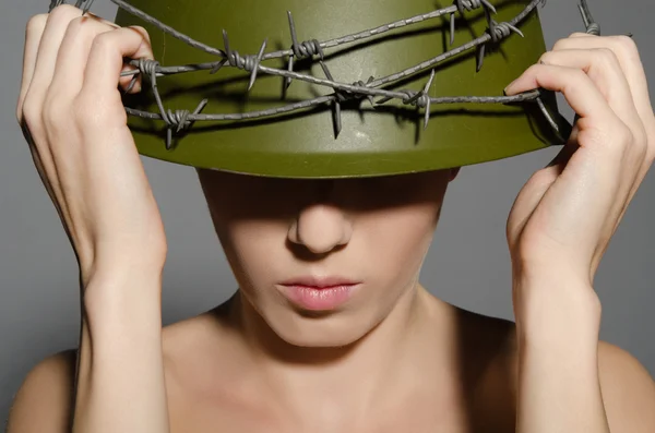 Woman holding hands military helmet with barbed wire