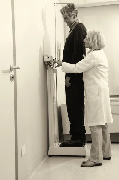 Man standing on weight machine with female doctor analyzing resu