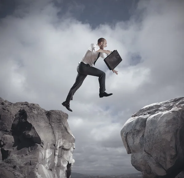 Businessman jumping over the mountains