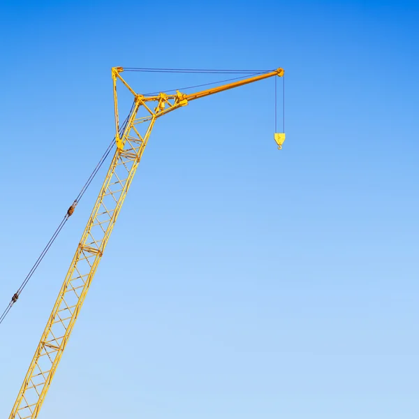Hoisting crane against the blue sky
