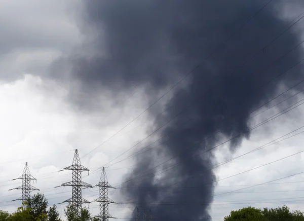 Black smoke over an industrial area and high voltage power lines