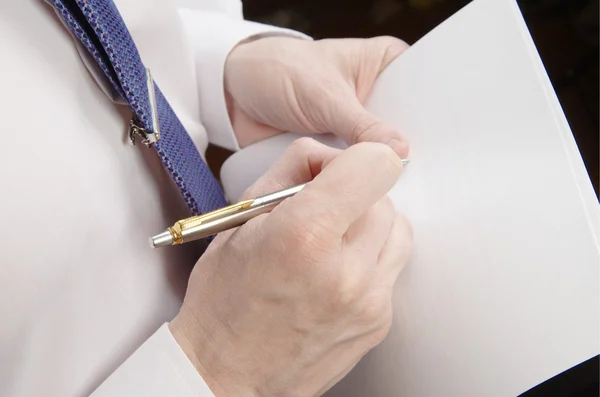 Businessman holding sheet of paper and pen