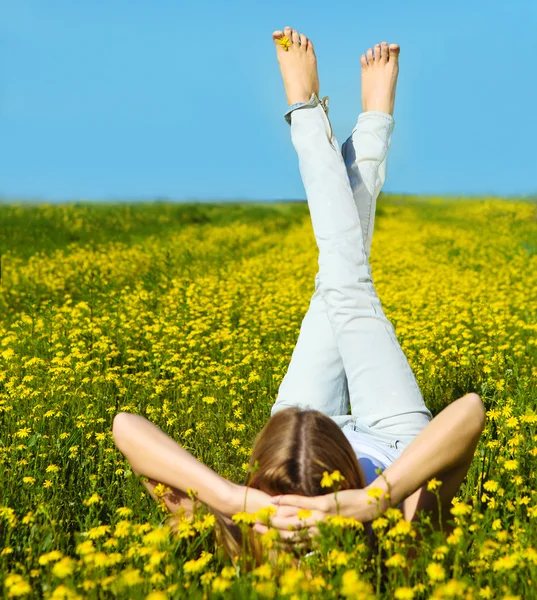 Young beautiful blond girl laying on the daisy flowers field