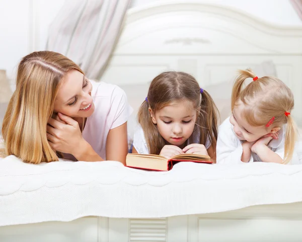 Mother and her daughters reading bed time story book