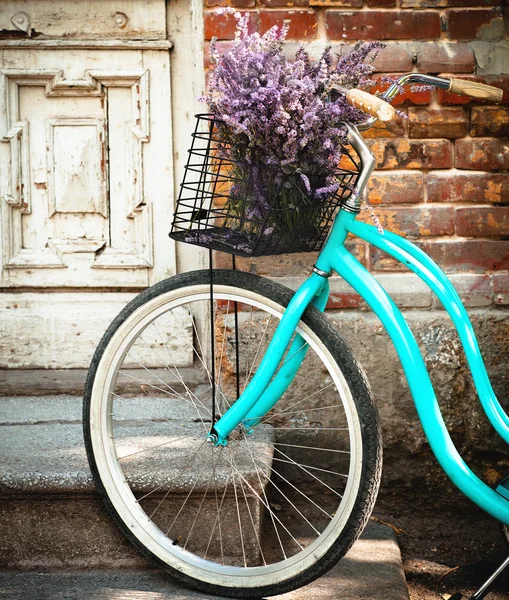 Vintage bycycle with basket with lavender flowers near the woode