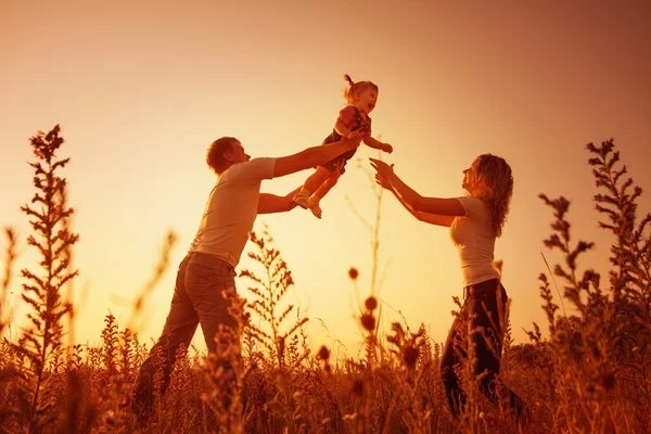 Happy family outdoor, silhouettes on sunset