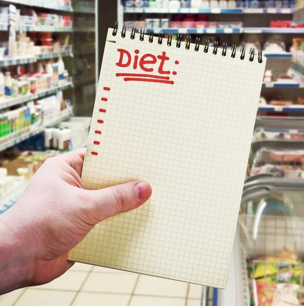 Hand holds a notebook with diet plan