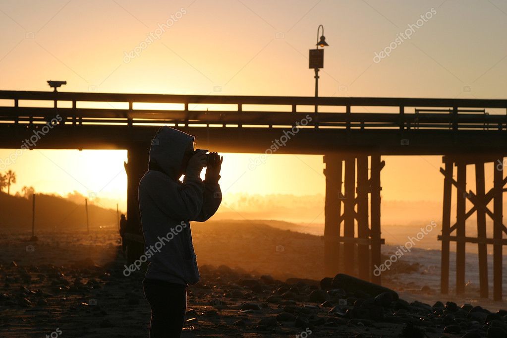 摄影师在日落日出的海滩和海洋码头附近– 图库图片