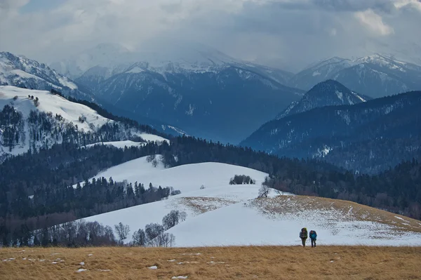A couple of backpackers walking faw away in winter mountains scenery