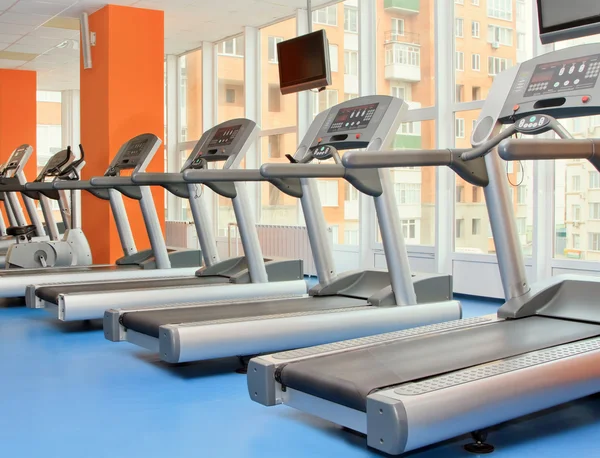 Gym with windows and running machines in fitness center