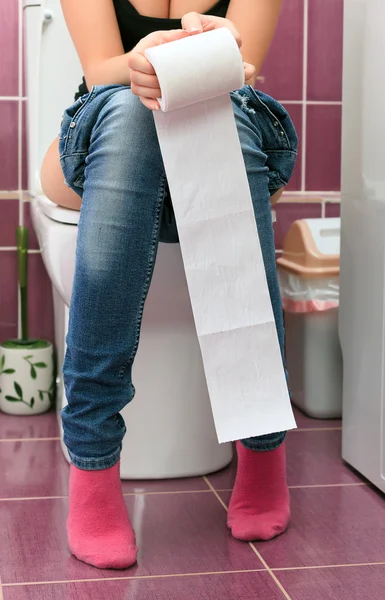 Woman in a toilet with a big hank of sanitary paper