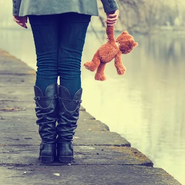 Lonely girl with teddy bear near river