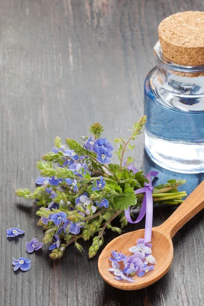 Essential oil, wooden spoon and healing flowers