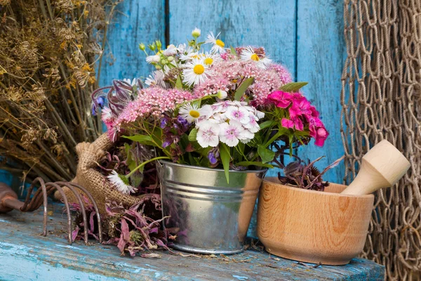 Flowers in bucket and mortar with healing herbs