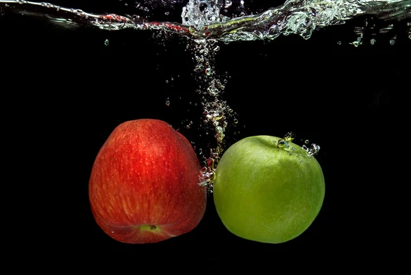 Ref and green apple dropped into water