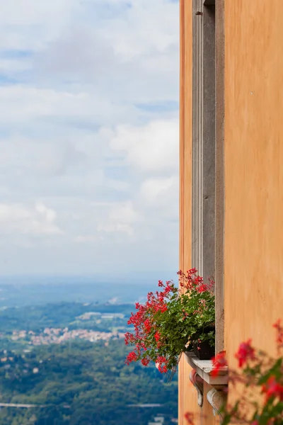 Flowers on the window against view of italian city in mountains