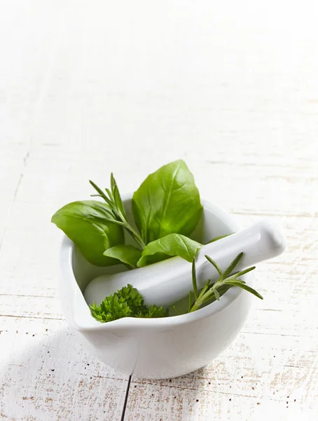 Green herbs in a mortar and pestle