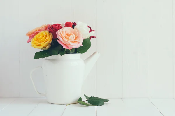 Colorful roses in white enamel coffee pot