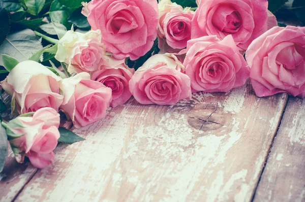 Pink roses on old wooden board