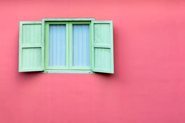 Vintage window with green shutters on pink wall