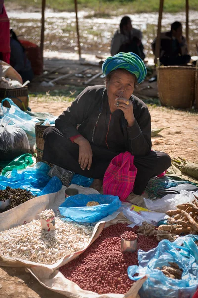 Burmese woman smoke cheroot cigar and sell on an open market