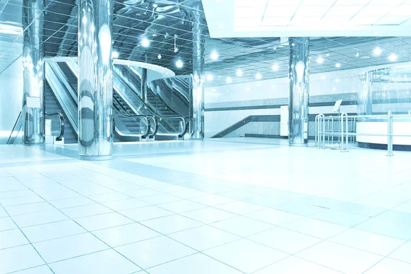 Contemporary moving escalator stairs inside business blue hall