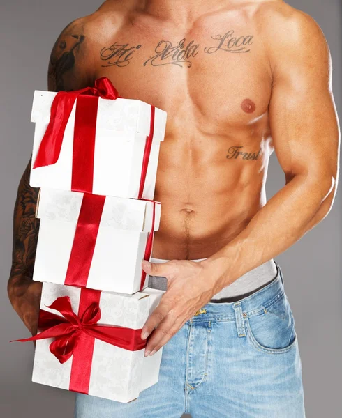 Man with tattooed muscular torso with gift boxes