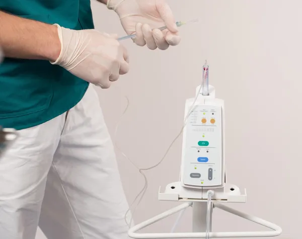 Doctor with intravenous pump machine in dental surgery