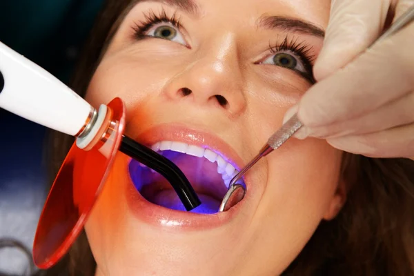 Young woman patient stopping treatment with dental UV light equipment