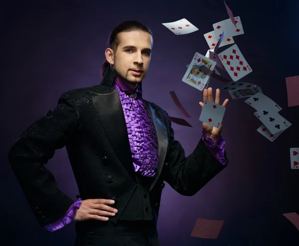 Young brunette magician in stage costume showing card tricks
