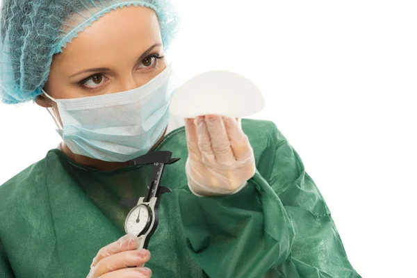 Plastic surgeon woman with silicon breast implants and calliper