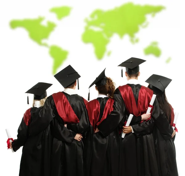 Group of graduated young students in black mantles against world map