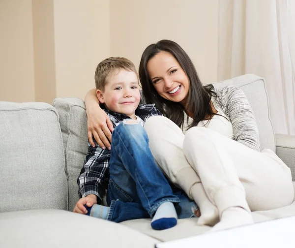Happy young mother with her son on a sofa in home interior