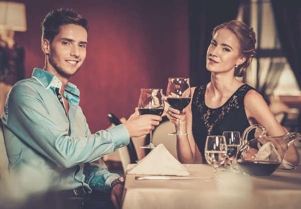 Beautiful young couple with glasses of wine in restaurant