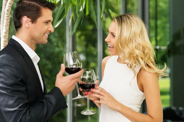 Cheerful couple with glasses of red wine talking