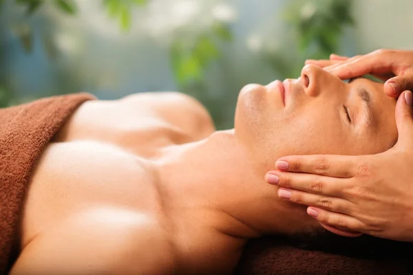 Handsome man having face massage in spa salon