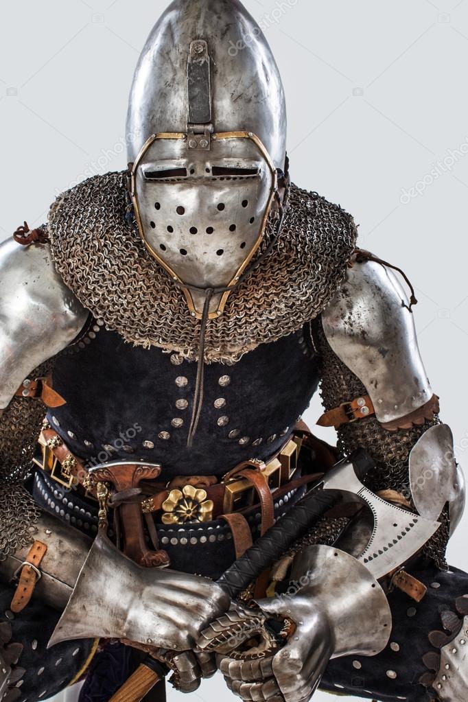 Man is posing in a knight armor while sitting on the chair — Stock