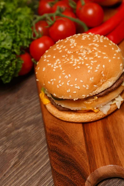 Big Mac on a wooden board and vegetables