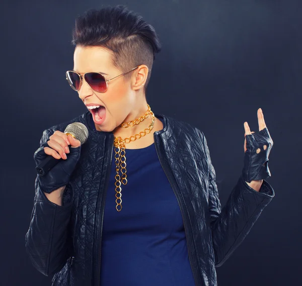 Passionate woman wearing sunglasses singing into microphone