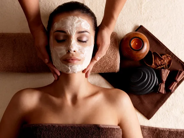 Spa massage for woman with facial mask on face